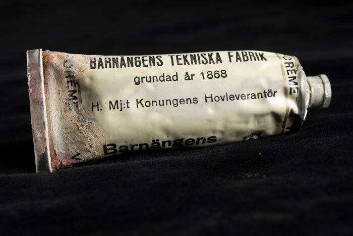 Metalltub med text "Barnängens Tekniska Fabrik", grundad 1868, och "H. Mjt Konungens Hovleverantör" synlig.