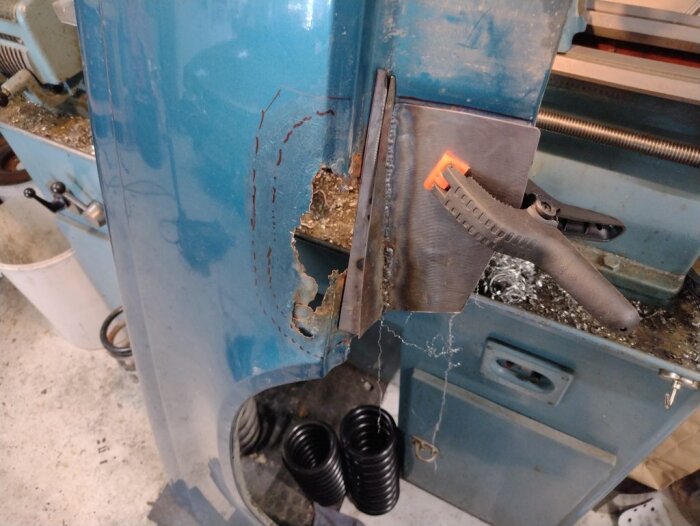 Reparation av framskärm på Volvo, visar ett inställt metallstycke fastklämt och förberett för svetsning på en verkstadsbänk.