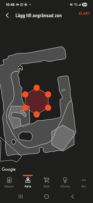 Karta på mobilapp som visar en avgränsad zon i rött med orange punkter, omgiven av grå områden.