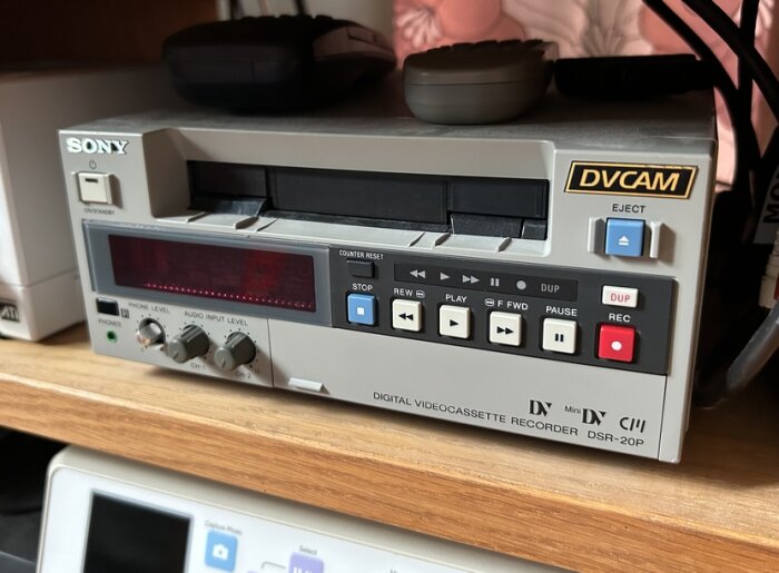 Digital videobandspelare Sony DSR-20P med kontrollknappar och anslutningar, placerad på en trähylla.