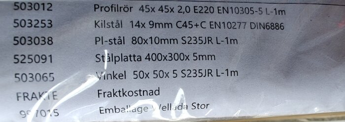 Etikett med information om byggmaterial som profildör, kilstål, pl-stål, stålplatta och vinkel, med dimensioner och specifikationer.