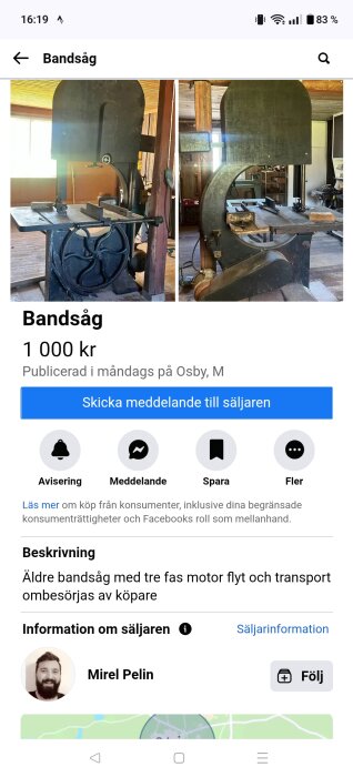 Äldre bandsåg med stort hjul och metallbord i en verkstadsmiljö, omgiven av träväggar och verktyg.