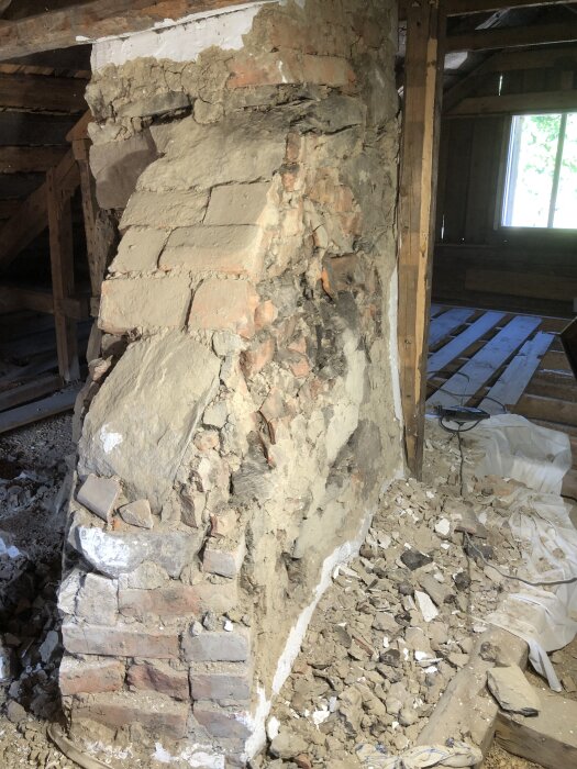 Skadad skorsten med bitar av tegel, stenar och takpannor. Mycket puts har fallit av och ligger på golvet i det gamla husets vind.