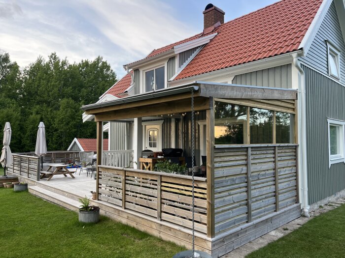 Innesluten altan på ett hus med tak av röda takpannor, träpanel och nyinstallerade fönsterkassetter för att skydda mot regn.