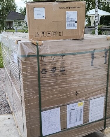 Paket och kartonger staplade utomhus, med en etikett som visar "solplanet.net".