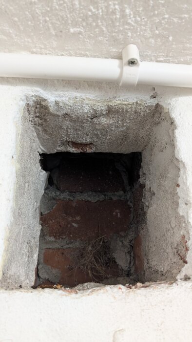 Ventilationskanal i murstock med synliga tegelstenar och smutsavlagringar i ett 50-talshus.