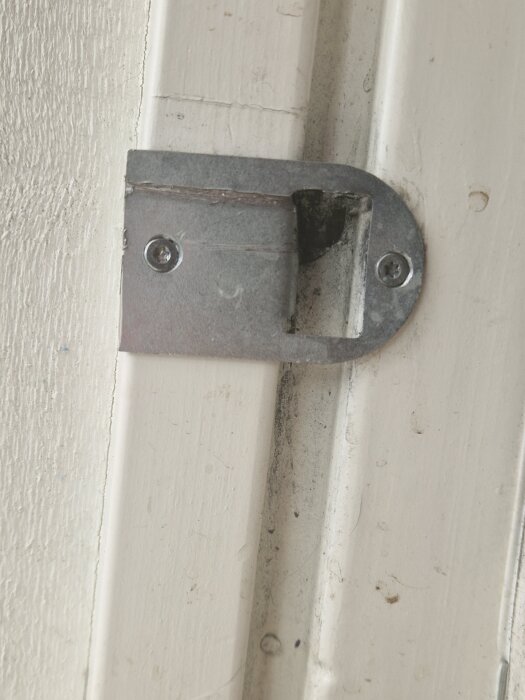 Metalldel på en dörrkarm visar skav från altandörrens kolvar, vilket orsakar problem med att låsa handtaget; bilden illustrerar justeringsbehovet.