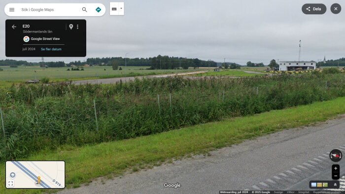Landskapsvy från E20 i Södermanlands län med omgivande ängar, buskar och ett vitt bygge i bakgrunden.