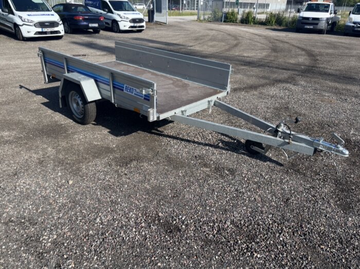 En släpvagn på en grusplan med öppna lämmar och utan baklampor.