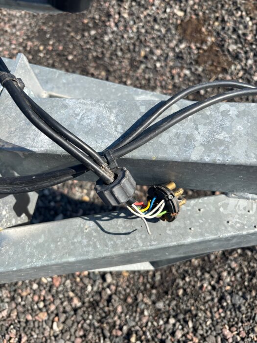Släpvagnskontakt med exponerade färgade kablar på metallram.