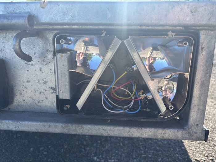 Trasigt baklyse på släp med synliga kablar och reflekterande yta, utan glas.