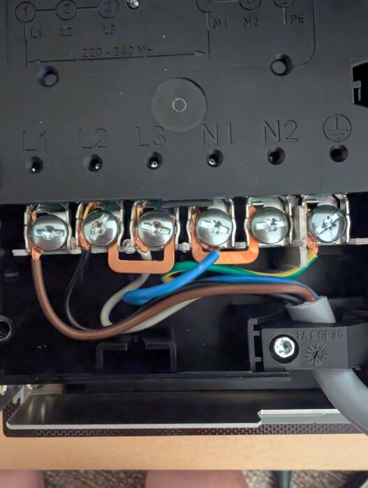 Nära bild av elektrisk kopplingsbox med flera färgade kablar anslutna till terminaler märkta L1, L2, L3, N1 och N2.