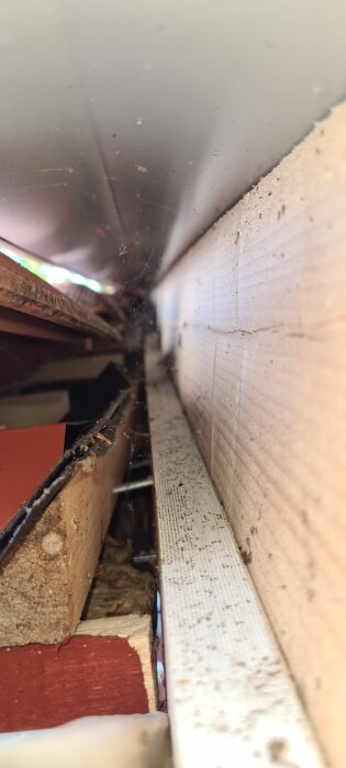 Anslutning mellan tak och vindskiva med synligt trä under papp. Frågeställning om korrekt installation och risk för läckage.