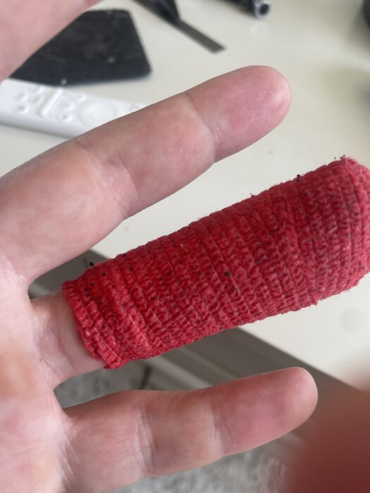 Ett finger med röd bandage som täcker skadan efter en klämskada under ett byggprojekt.
