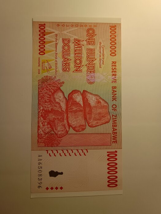 Zimbabwisk sedel på hundra biljoner dollar med stenar och nummer 100000000.