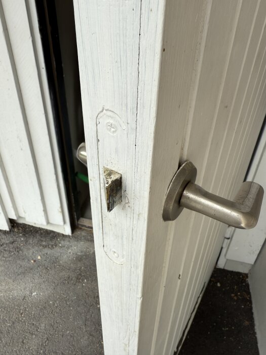 Trädörr med silverfärgat handtag och ingenting annat monterat, i behov av ett lås.