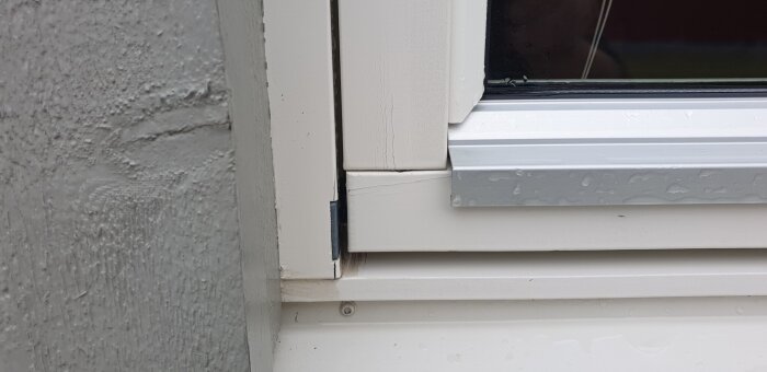 Närbild på ett fönster från 2008 med fokus på en skarv utan lodrät anslutning, visar en del av karmen och droppande regn på listen.
