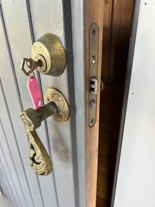 Dörr med en Abloy 4260 låskista, nyckel i cylindern och ett gammalt dörrhandtag visar en dörr som är delvis öppen.
