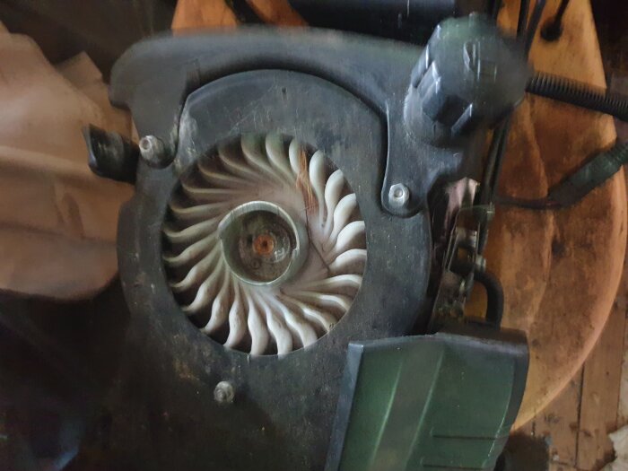 Bild av en del av en motor eller maskindel, med synliga fläktblad och kablar.