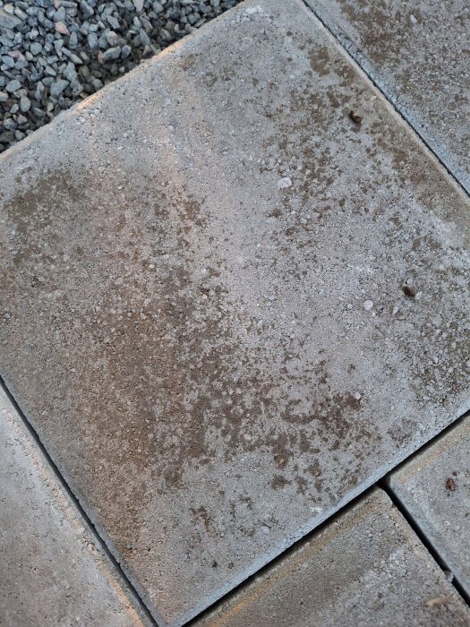 Närbild på betongplattor lagda i ett hörn, med synlig struktur och grus i fogarna.