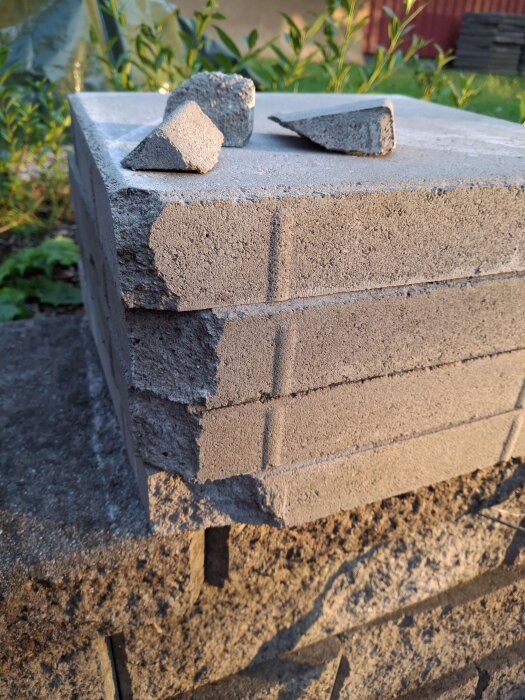 Betongplattor staplade på varandra med några spruckna bitar ovanpå, används som underlag för växthusbyggande.