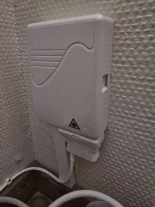 Väggmonterad elektrisk dosa med varningstriangel, kabelansluten, inomhus.