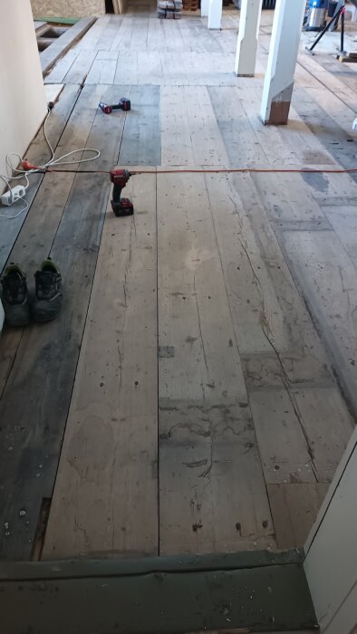 Nyslipat trägolv med skruvdragare och arbetsredskap i bakgrund.