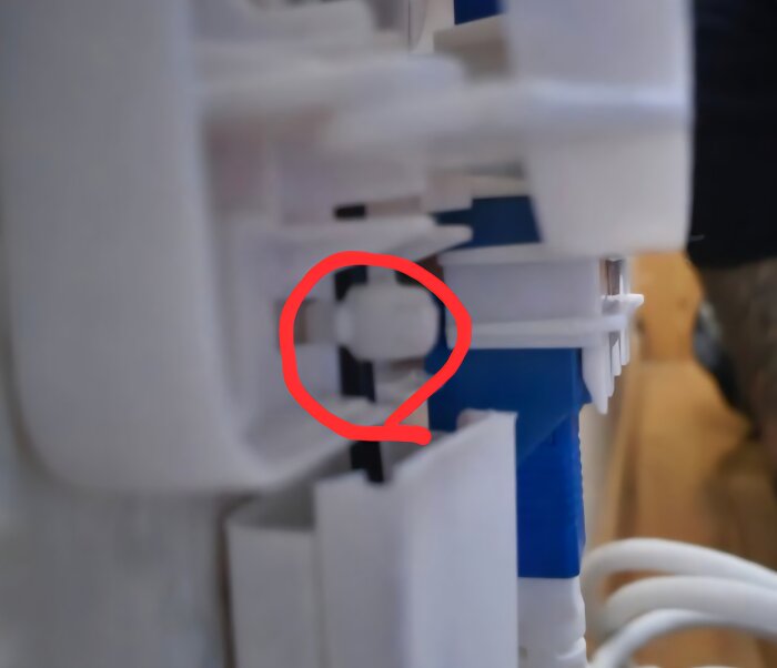 Inringad klämma som håller en vit 5 mm duct i en kopplingsbox, med fokus på att inte dra i fiberdosan eller låta kontakterna vidröras.