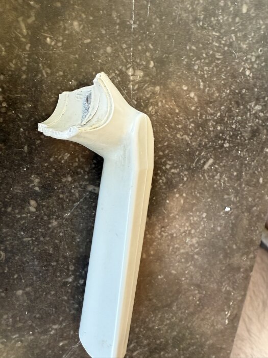 Trasigt gammalt fönsterhandtag från 50-talet i två delar på en marmorerad yta, ingen synlig skruv.