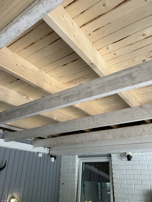 Trätakstruktur med reglar över en inglasad altan. Reglarna kopplar samman taket med husväggen.