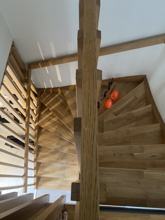 Spiraltrappa i ek färdigbyggd med ekfoder, visad från ovan, verktyg och orange föremål syns längre ner.