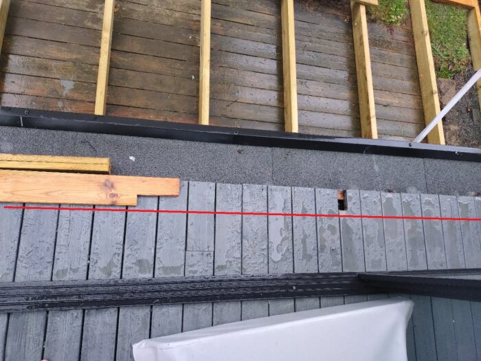 Byggprojekt av trappa från altan, med trall vid pergola. En röd linje visar perspektivskillnad mellan pergola och altanens kant. Monterade reglar syns.