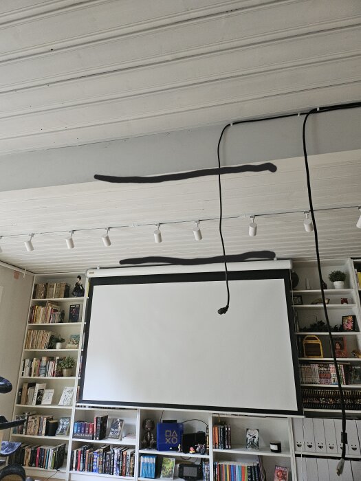 Projektorduk framför bokhylla, tak med svarta streck markerar möjliga platser för montering av soundbar.