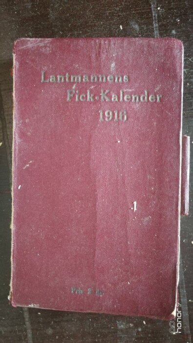 Röd bokomslag med texten "Lantmannens Fick-Kalender 1916" tryckt på framsidan.