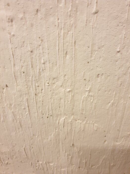 Vägg med fuktfläckar och oregelbunden yta, tecken på att torka med hjälp av fläkt och avfuktare.