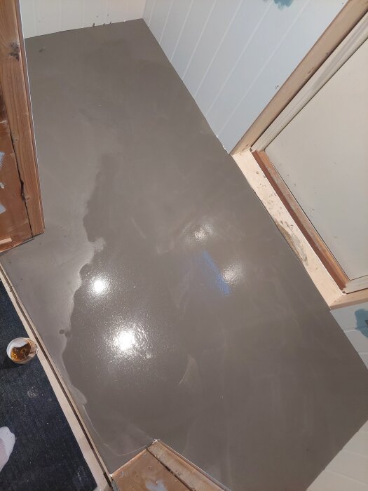 Nylagd flytspackel på golv i ett rum under renovering, med vattenpass justerat.
