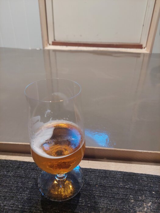 Ett glas med öl står framför ett nylagt golv av flytspackel.
