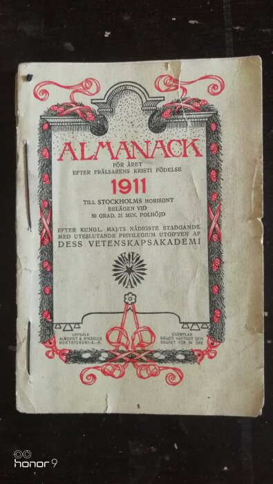 En gammal almanacka från 1911 med dekorativa element i rött och svart, publicerad av Dess Vetenskapsakademi, tryckt i Uppsala.