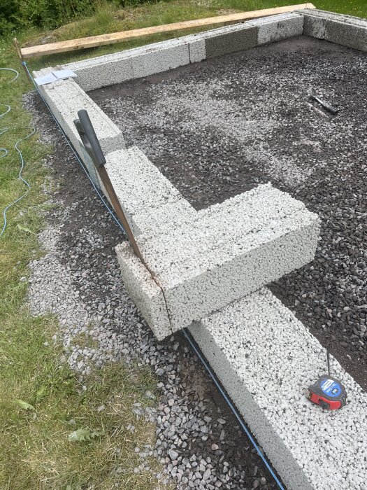 En grund av lättbetongblock lades samman i en rektangulär form, omgiven av grus och gräs, med ett måttband liggande på kanten.