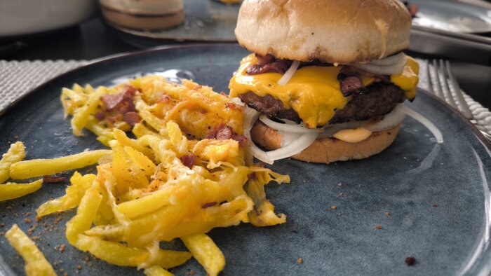 Hamburgare med ost, lök och dressing på en tallrik bredvid pommes frites.