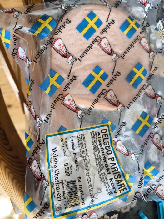 Förpackning med Delsbo Parisare, svensk grillkorv, dekorerad med svenska flaggor och logotyp för Delsbo Charkuteri.