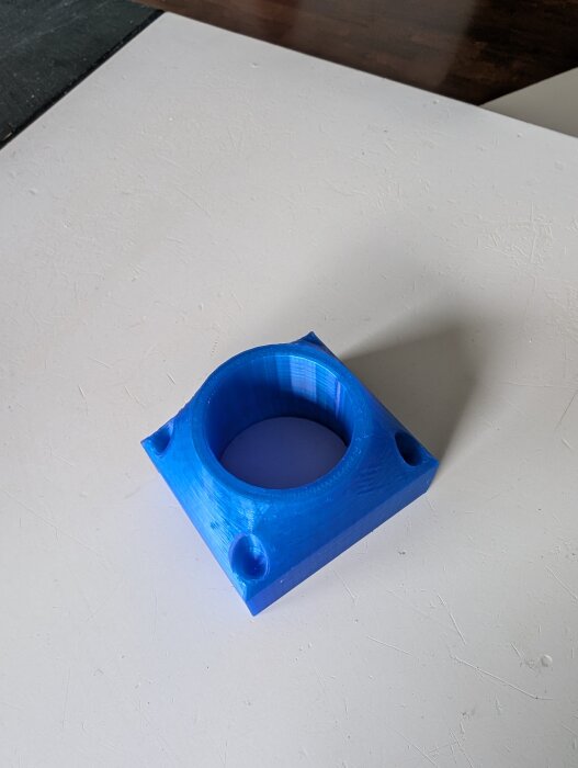 3D-printad plastadapter för anslutning av dammsugare till en pocket hole jig, visad i blått med borrade hål för montering.