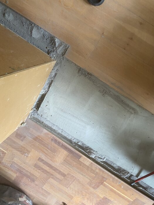 Hål i golvet efter rivning av vägg, trä- och betongytor synliga, redo för att fyllas och jämnas ut inför ny väggkonstruktion och golvläggning.