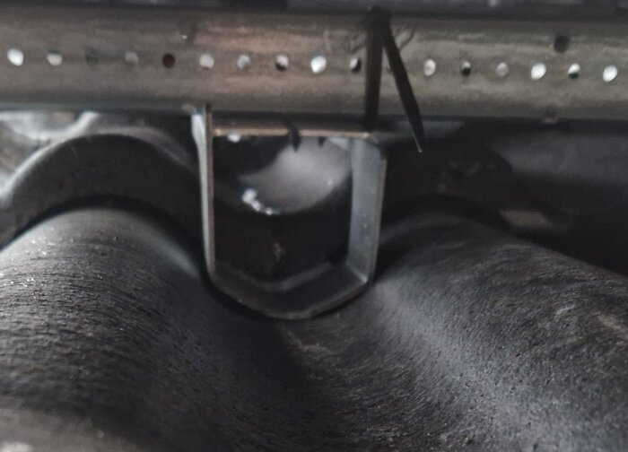 Närbild på takkrok och takpannor med monteringsdelar för solpaneler.