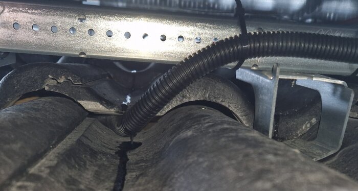 Skadad takpanna med synlig kabeldragning och metallfäste.