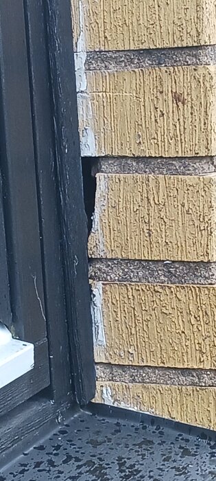 Skadad gul tegelsten vid fönster, visa en spricka eller skada som behöver åtgärdas. Frågor om byte eller risker vid utebliven åtgärd.