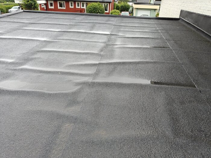 Vågigt garagetak med vattenansamlingar på vissa platser, vilket orsakar oro för avrinning och tätning vid temperaturvariationer.