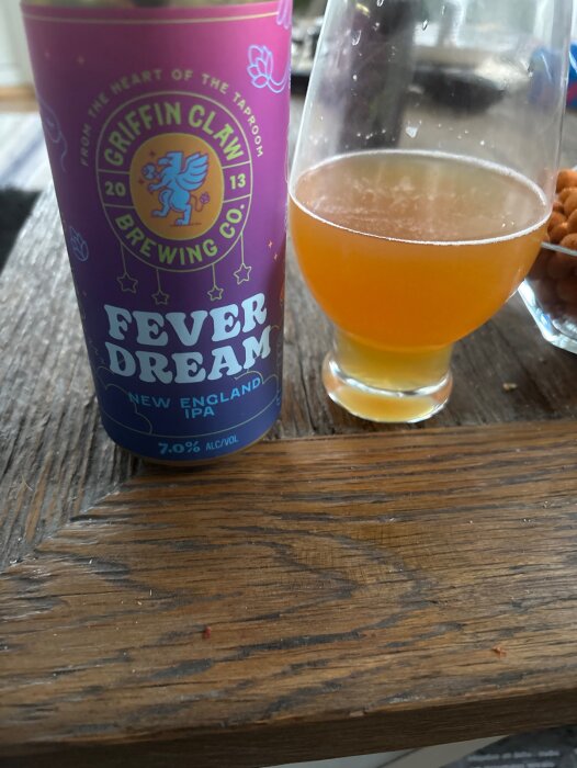 En burk Griffin Claw Brewing Co. Fever Dream New England IPA och ett glas med öl på ett träbord.
