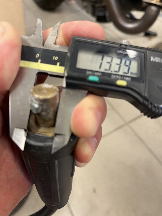 Mätning av axeldiametern på en pig-tail kontakt med ett digitalt skjutmått, som visar 13.39 mm.