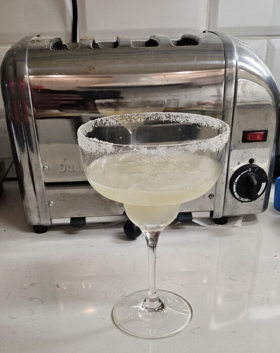 Frozen Margarita serverad i ett glas med saltad kant, stående framför en köksapparat på en köksbänk.